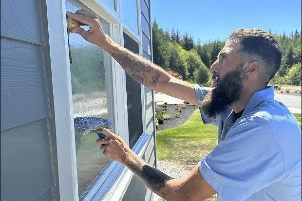 Professional window cleaner using equipment to clean windows safely