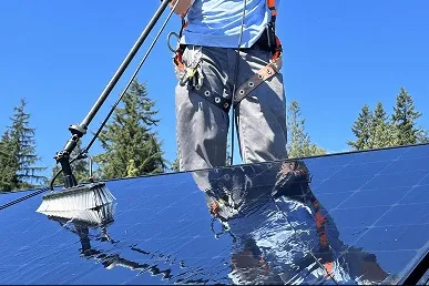 Technician cleaning rooftop solar panels with pure water system