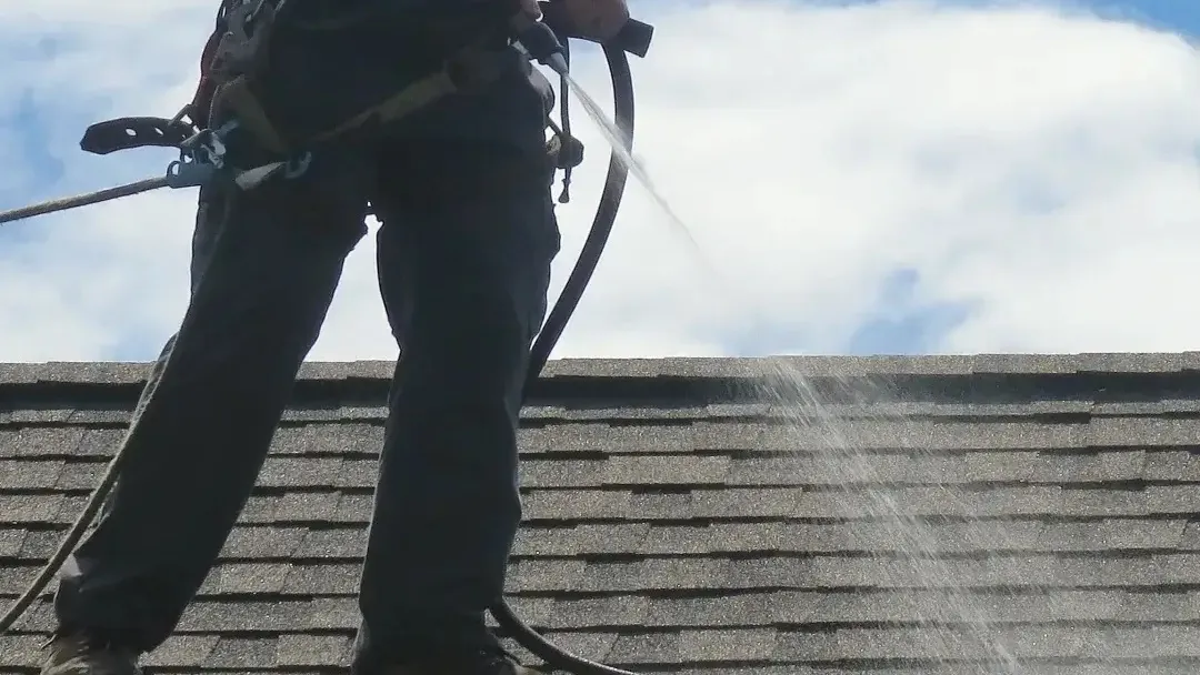 Technician performing exterior surface cleaning on a residential roof