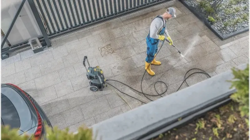 Worker pressure washing outdoor surfaces to remove stains and buildup